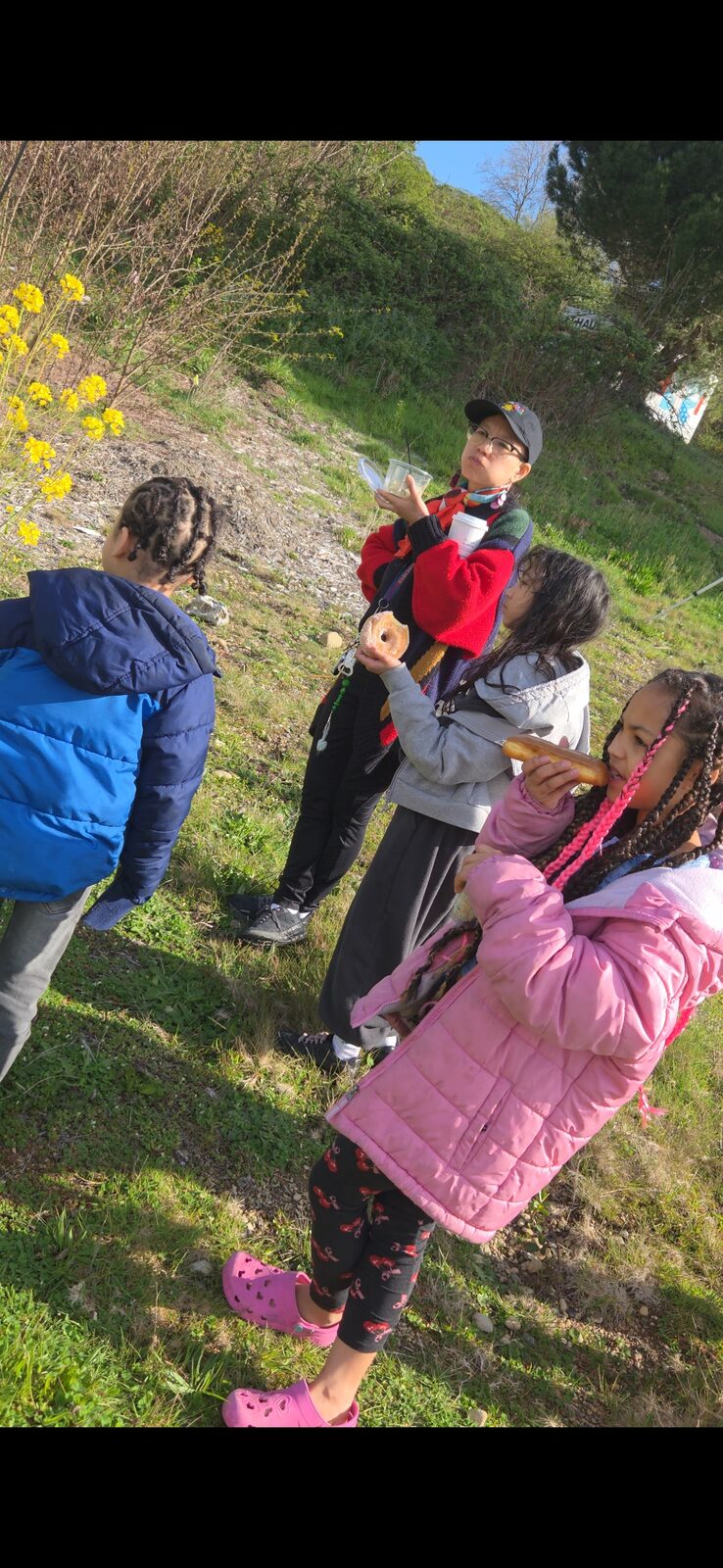 Cody facilitating a youth circle on a grassy hillside at NW Folklife