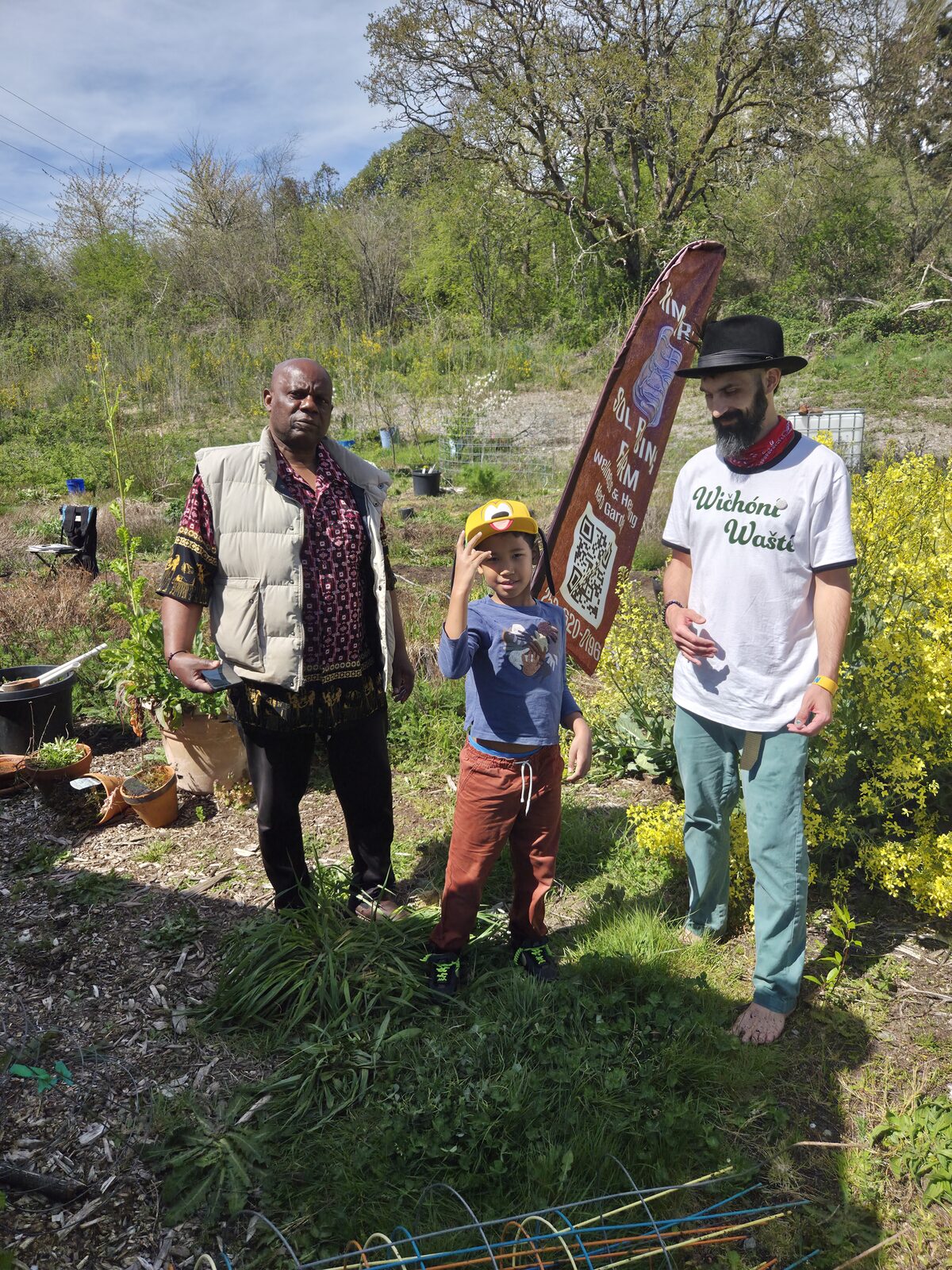 Cody, a young person in a Pikachu cap, and an elder in a patterned vest at Sol Rising Farm